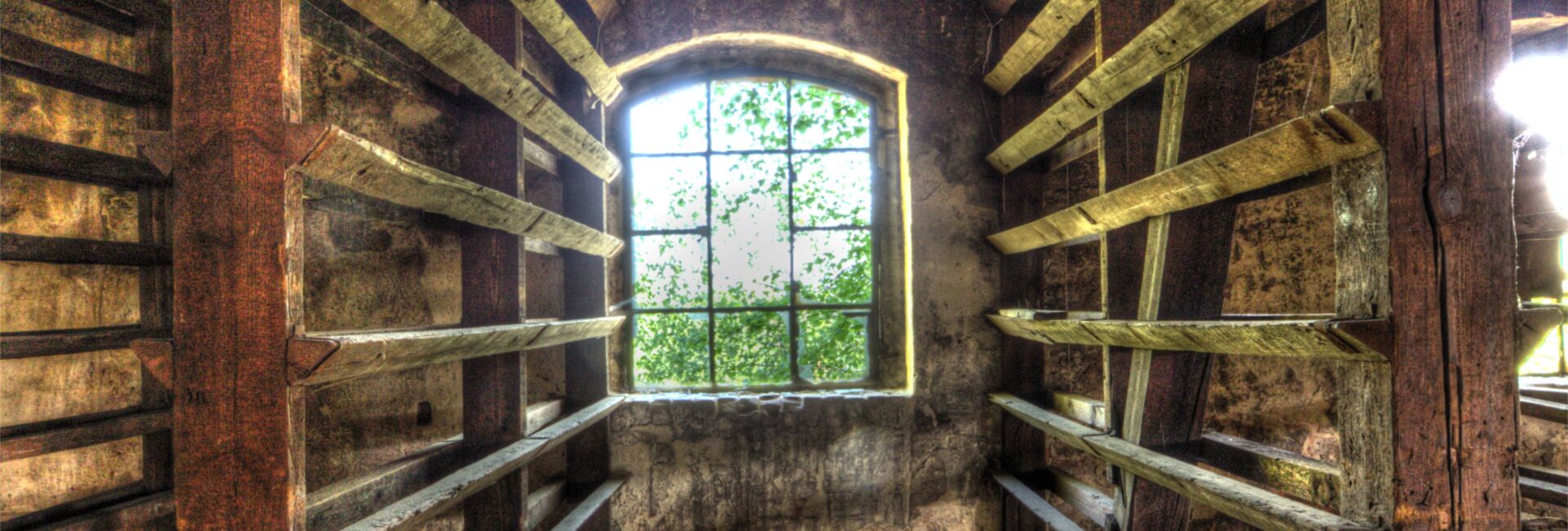 Verfallene Holzhalle mit Fenster und Regalen.