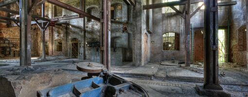 Alte Fabrikhalle mit Rost, Holz und zerfallenden Wauern.