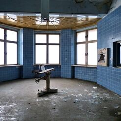 Runder, verlassener Raum mit blauen Fliesen.